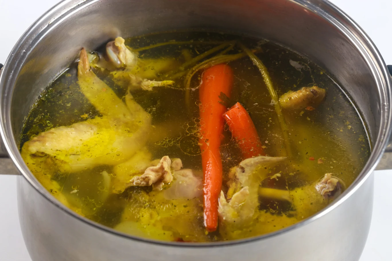 Opalona cebula nadaje rosołowi wyjątkowy, dymny aromat. Garnek z rosołem i warzywami.