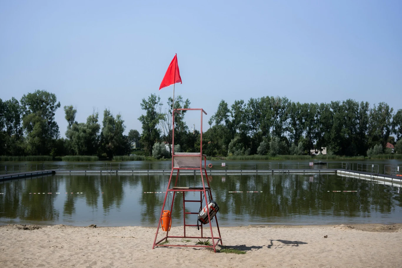 W jeziorze Średzkim jest wyjątkowo mało wody Czerwona flaga na wieży ratownika przy piaszczystej plaży nad niskim poziomem wody w jeziorze Średzkim.