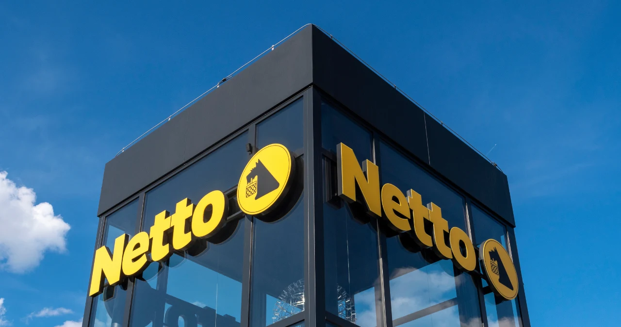 Netto urządziło mały „kącik kierowcy”. Ceny zaczynają się od zaledwie 7 zł Fasada sklepu Netto z żółtym logo na tle nieba, oferta produktów dla kierowców od 7 zł.