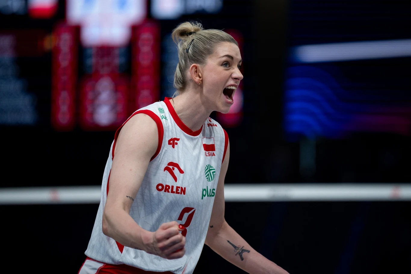 Zawodniczka siatkarskiej reprezentacji Polski w białym stroju z czerwonymi akcentami wyraża silne emocje po udanej akcji na boisku.