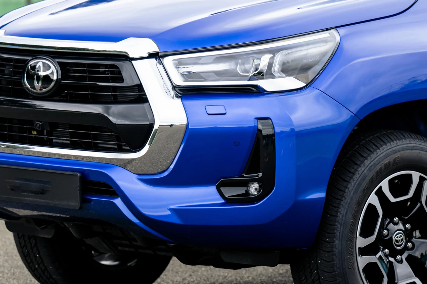 Toyota Hilux w wersji Executive i pakietem Sport teraz w niższej cenie Toyota Hilux Executive z pakietem Sport, widoczny przedni fragment niebieskiego pickupa z grillem i reflektorami LED