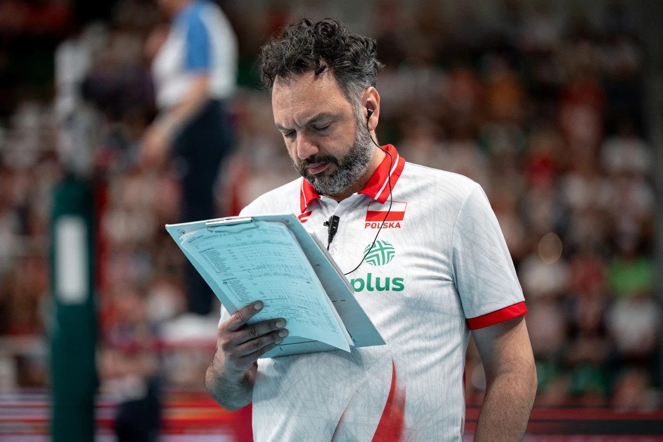 Stefano Lavarini od tego sezonu ma w sztabie trenerkę Trener reprezentacji Polski w siatkówce analizuje notatki na boisku podczas meczu, skupiony na dokumencie trzymanym w rękach.