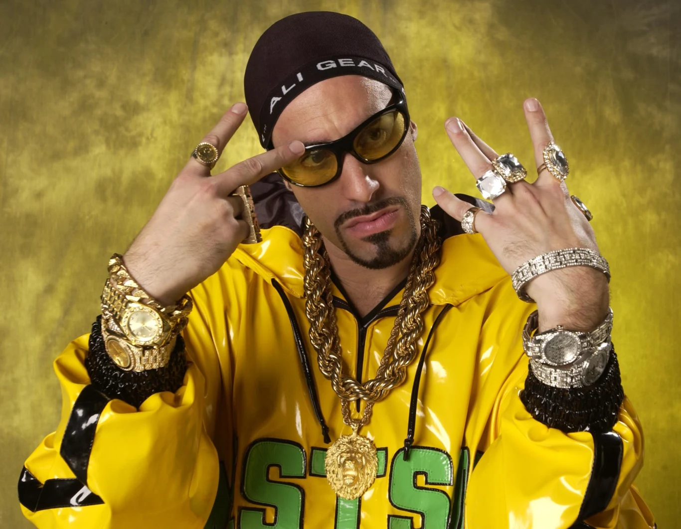 Sacha Baron Cohen jako Ali G w 2001 roku Sacha Baron Cohen jako Ali G w 2001 roku, w żółtej kurtce, z biżuterią, czapką i okularami przeciwsłonecznymi.