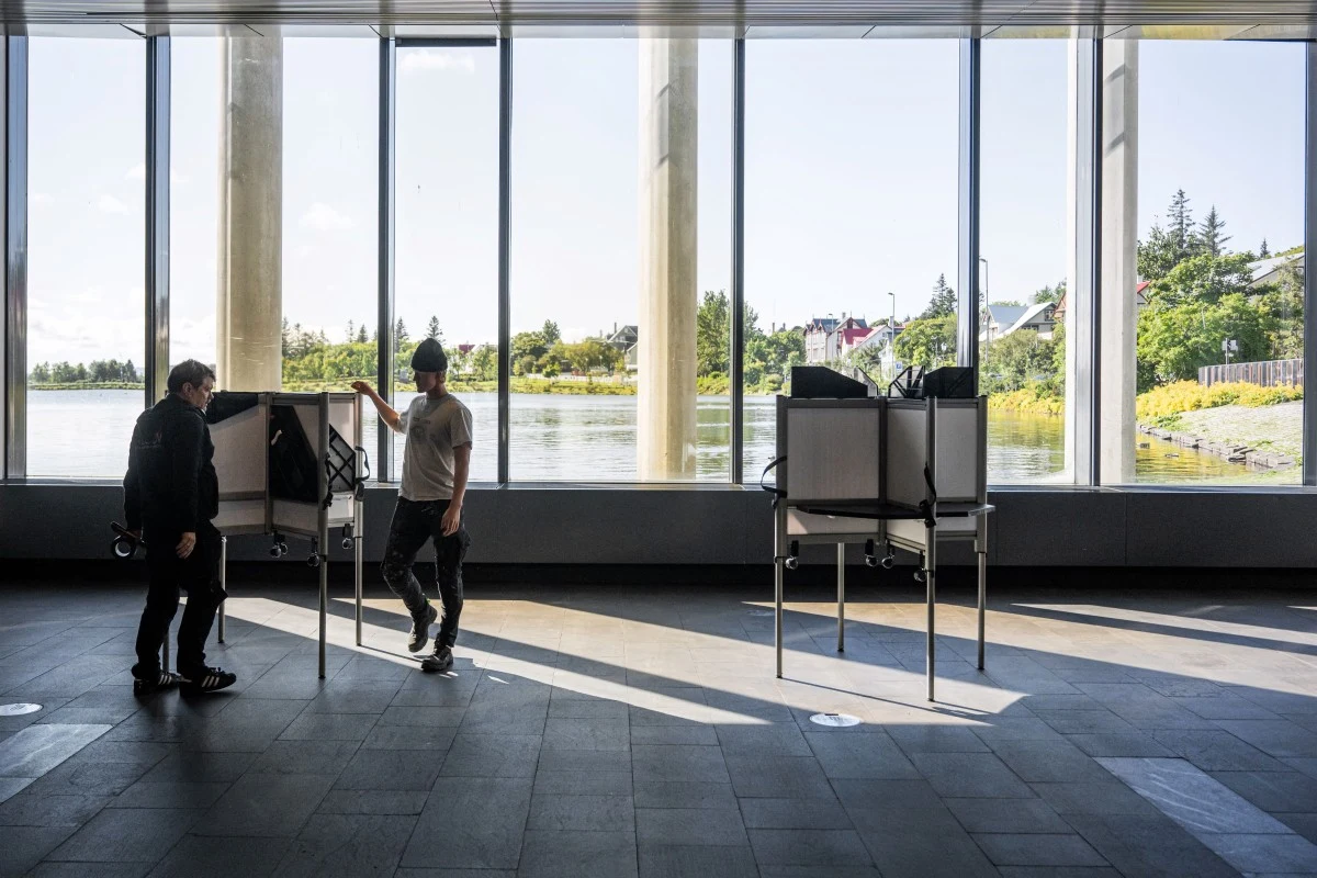 Islandia szykuje się na referendum ws. przyszłości w Unii Europejskiej Dwie osoby głosujące w kabinach, przy dużych oknach z widokiem na wodę i zieleń, przed referendum na Islandii.
