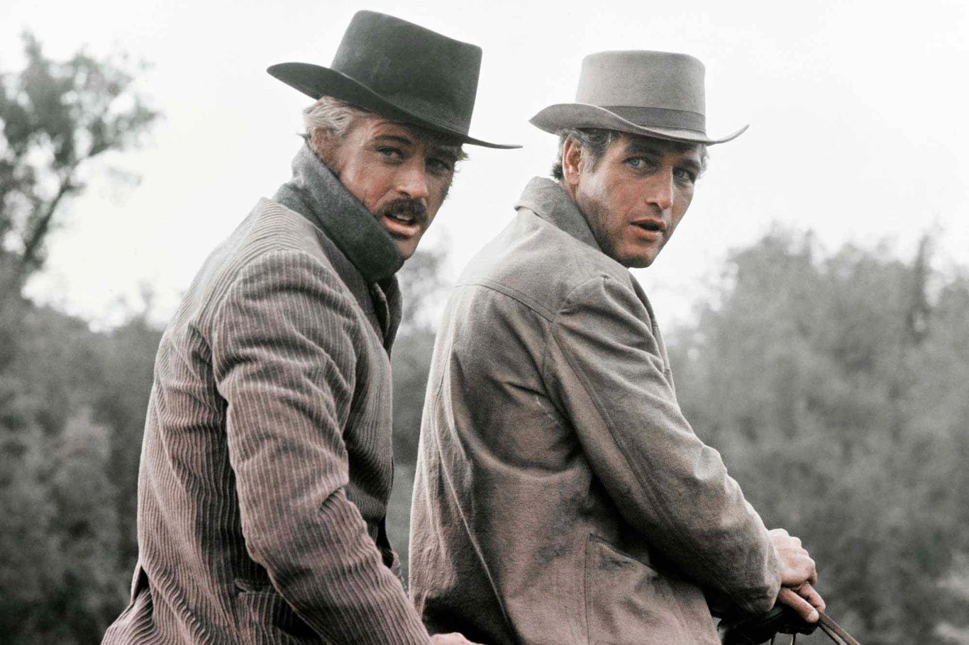 Paul Newman i Robert Redford Dwóch mężczyzn w kapeluszach i strojach charakterystycznych dla Dzikiego Zachodu siedzi obok siebie na koniu, patrząc w stronę obiektywu.