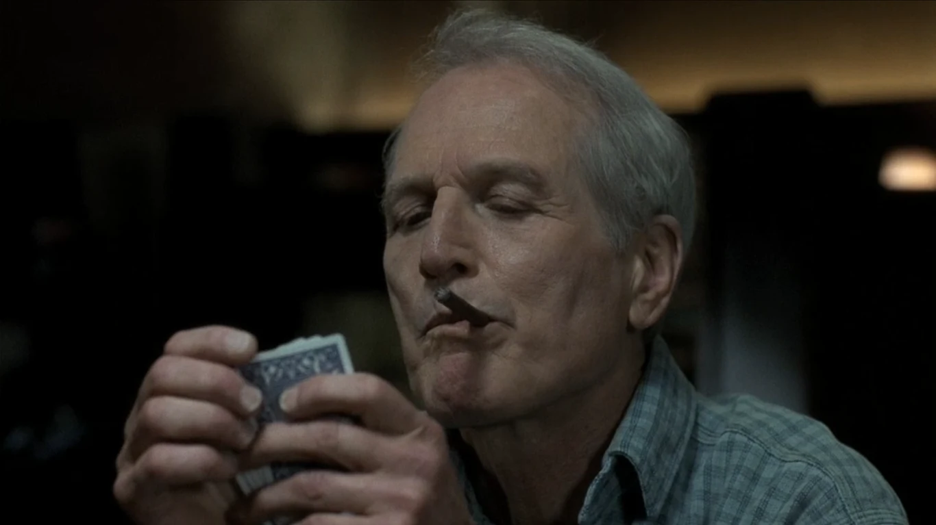Paul Newman w filmie Kolor pieniędzy Starszy mężczyzna w koszuli z zamkniętymi oczami trzyma talię kart do gry, z cygarem w ustach.