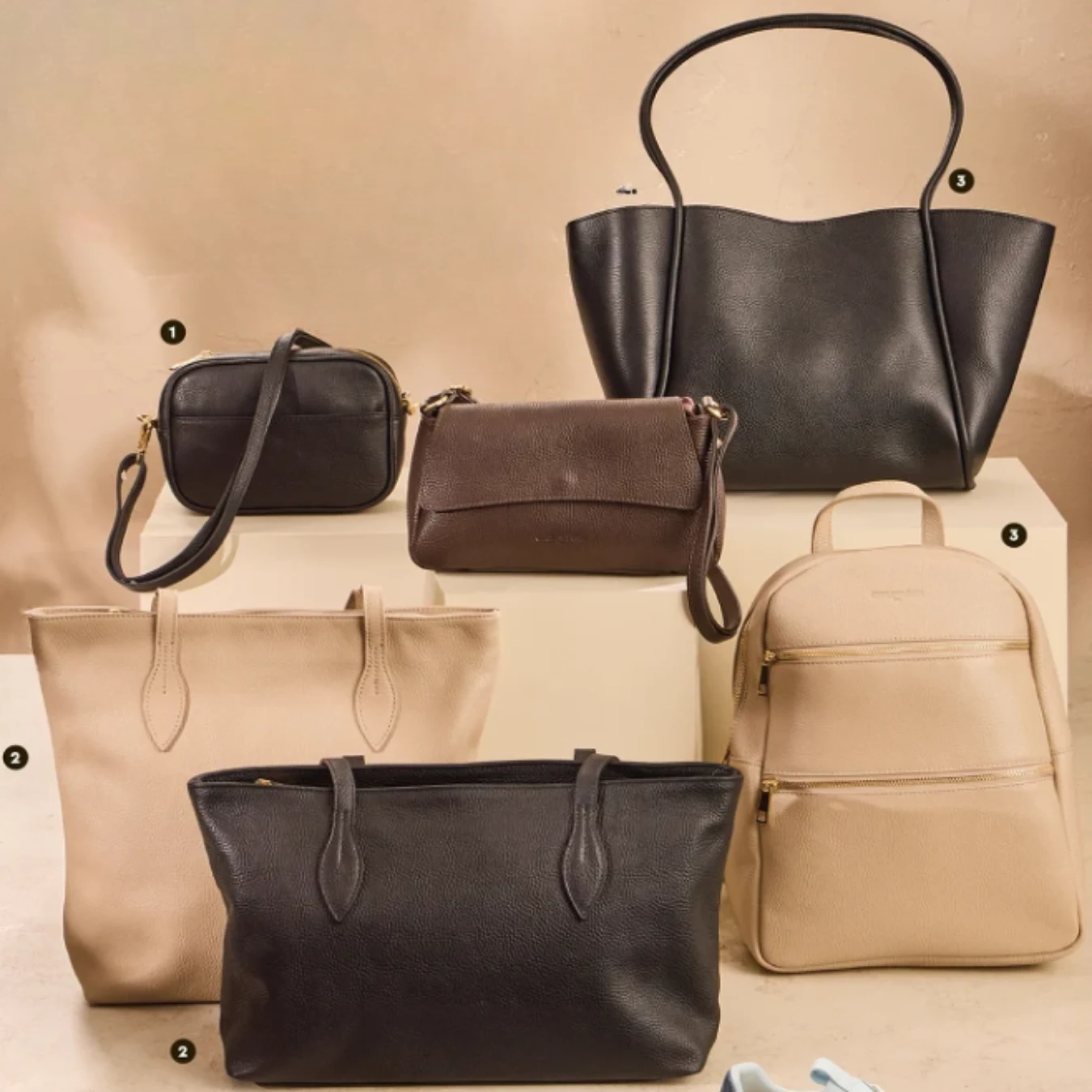Produkty skórzane marki Cholewiński Pięć eleganckich torebek w odcieniach czerni, brązu i beżu, wśród których znajdują się zarówno większe torby na ramię, jak i mniejsze modele oraz plecak, ustawione na jasnych geometrycznych podstawach.