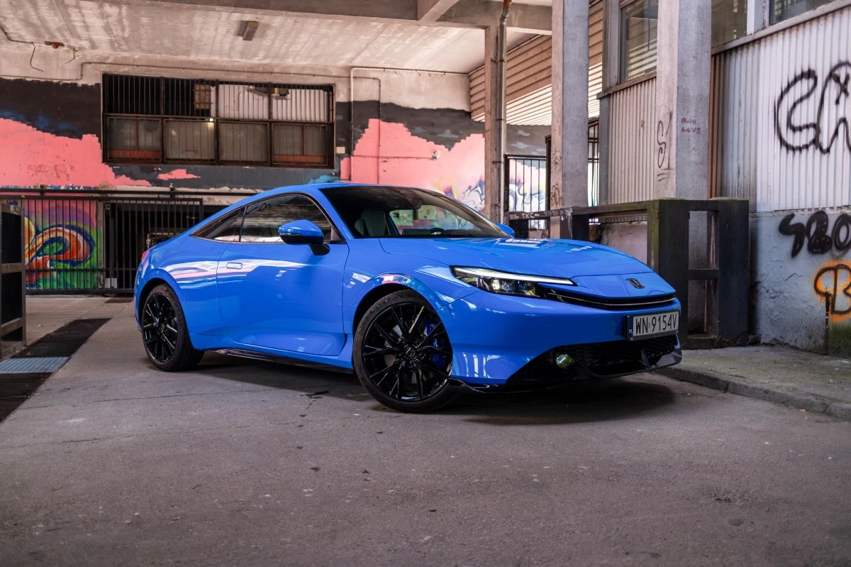 Linią nadwozia Prelude przypomina Peugeota RCZ albo Audi TT Sportowe coupe w intensywnie niebieskim kolorze z czarnymi felgami, zaparkowane w przestrzeni z betonowymi filarami oraz ścianami pokrytymi kolorowym graffiti.