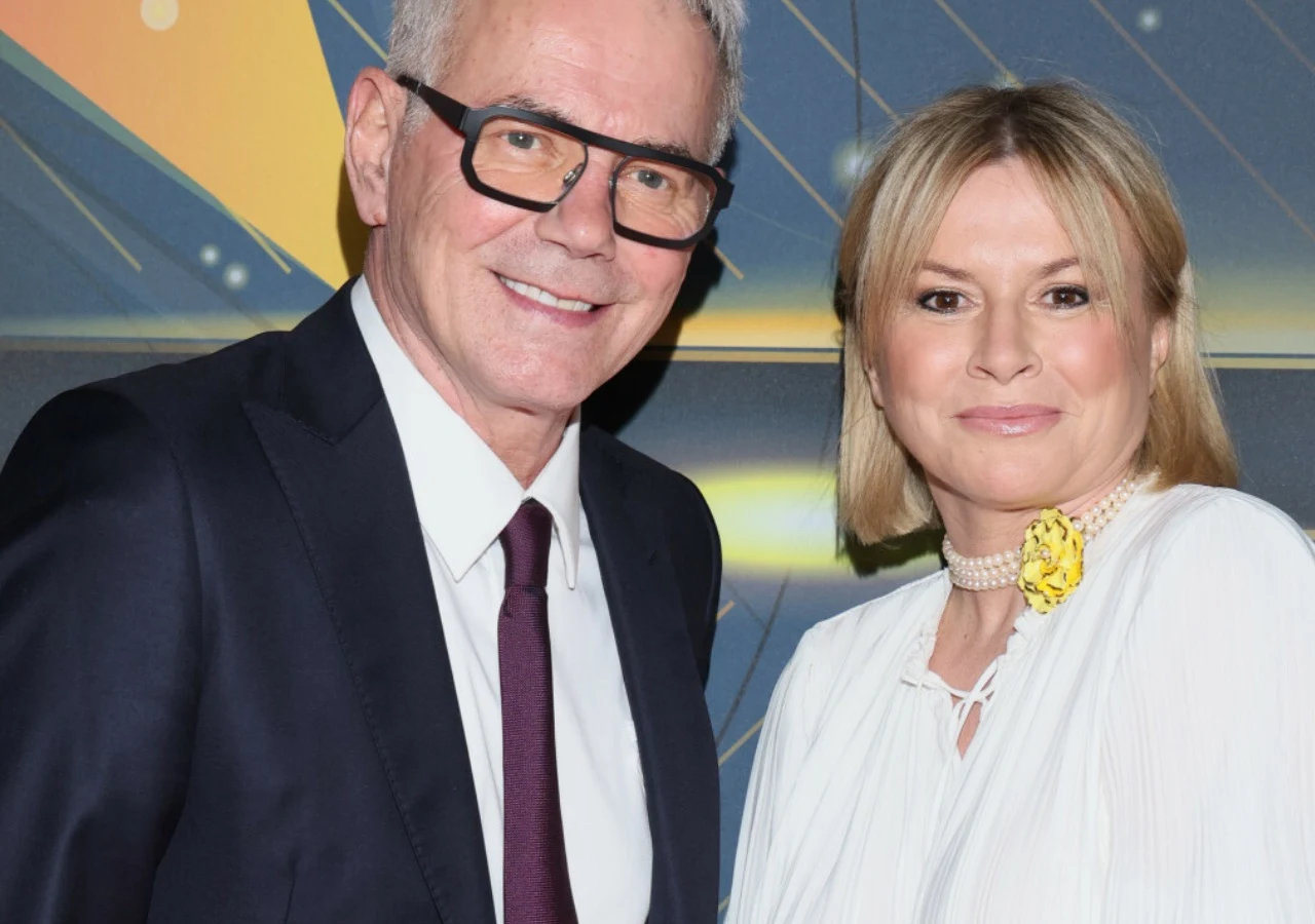 Robert Janowski i jego żona Monika Robert Janowski i jego żona Monika w eleganckich strojach pozują razem na tle dekoracyjnej ścianki.