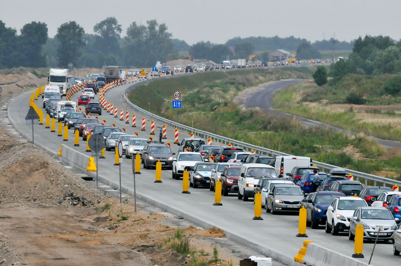Na Mazowszu w ciągu ponad 20 lat wybudowano i przebudowano łącznie ponad 855 km dróg. Zdjęcie ilustracyjne. Korek na autostradzie na Mazowszu, samochody stoją przy zwężeniu jezdni, żółte pachołki, prace drogowe.