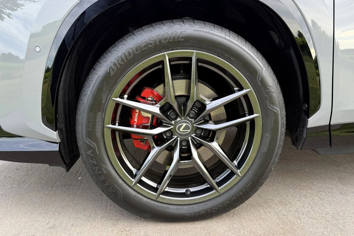 Pojawiły się nowe wzory felg w rozmiarach od 18 do 20 cali. Felga z charakterystycznym logo Lexus, niskoprofilowa opona Bridgestone oraz czerwony zacisk hamulcowy za szprychami koła.