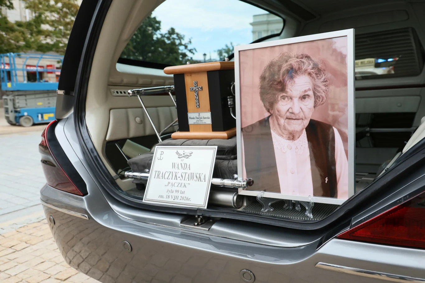 Uroczystości pogrzebowe Wandy Traczyk-Stawskiej, powstanki warszawskiej Uroczystości pogrzebowe Wandy Traczyk-Stawskiej, urna i zdjęcie w otwartym bagażniku karawanu.