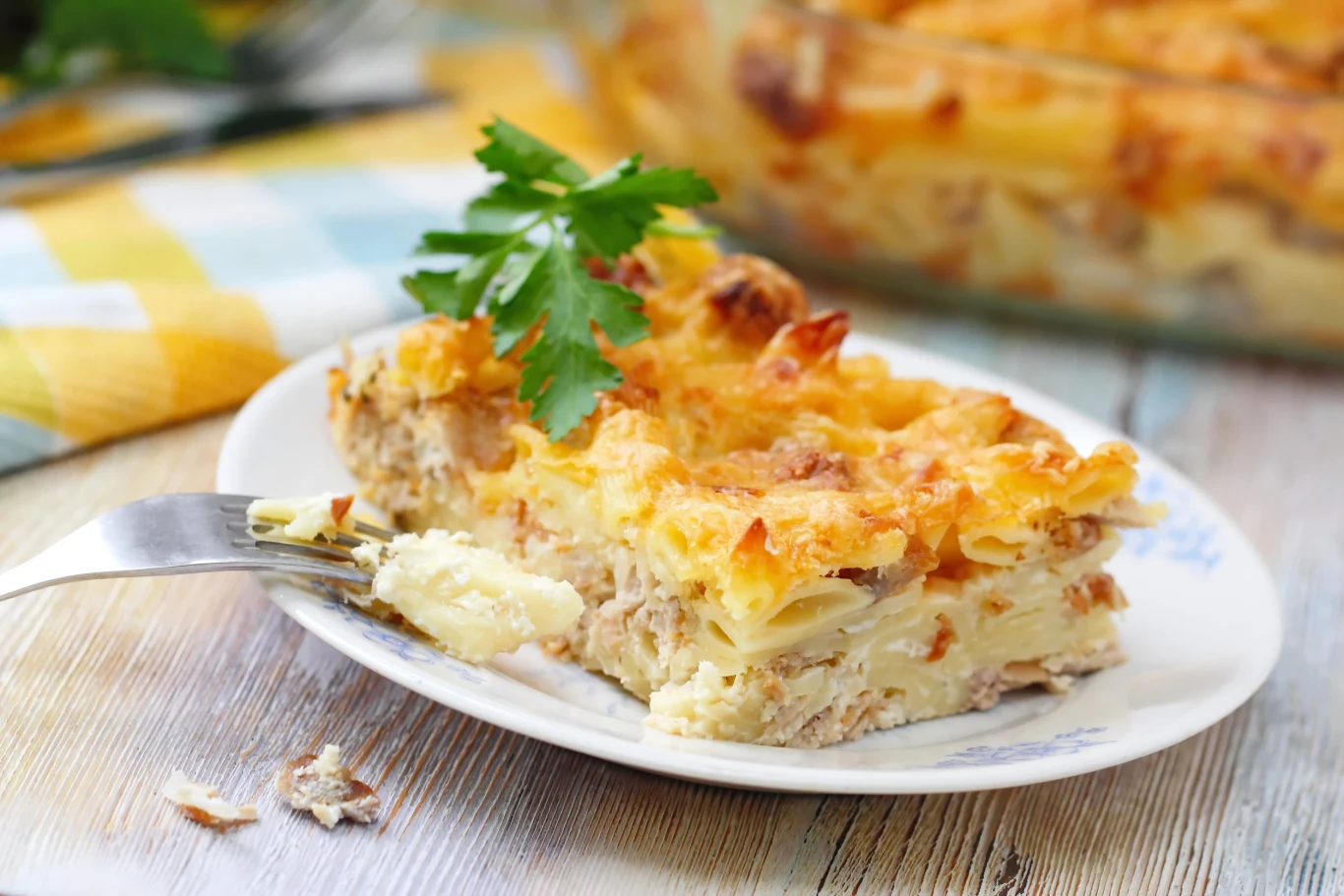 Zapiekanka gołąbkowa, kapusta i mięso mielone w aromatycznym daniu Zapiekanka gołąbkowa z kapustą, mięsem mielonym i serem, udekorowana natką pietruszki, na białym talerzu z widelcem.