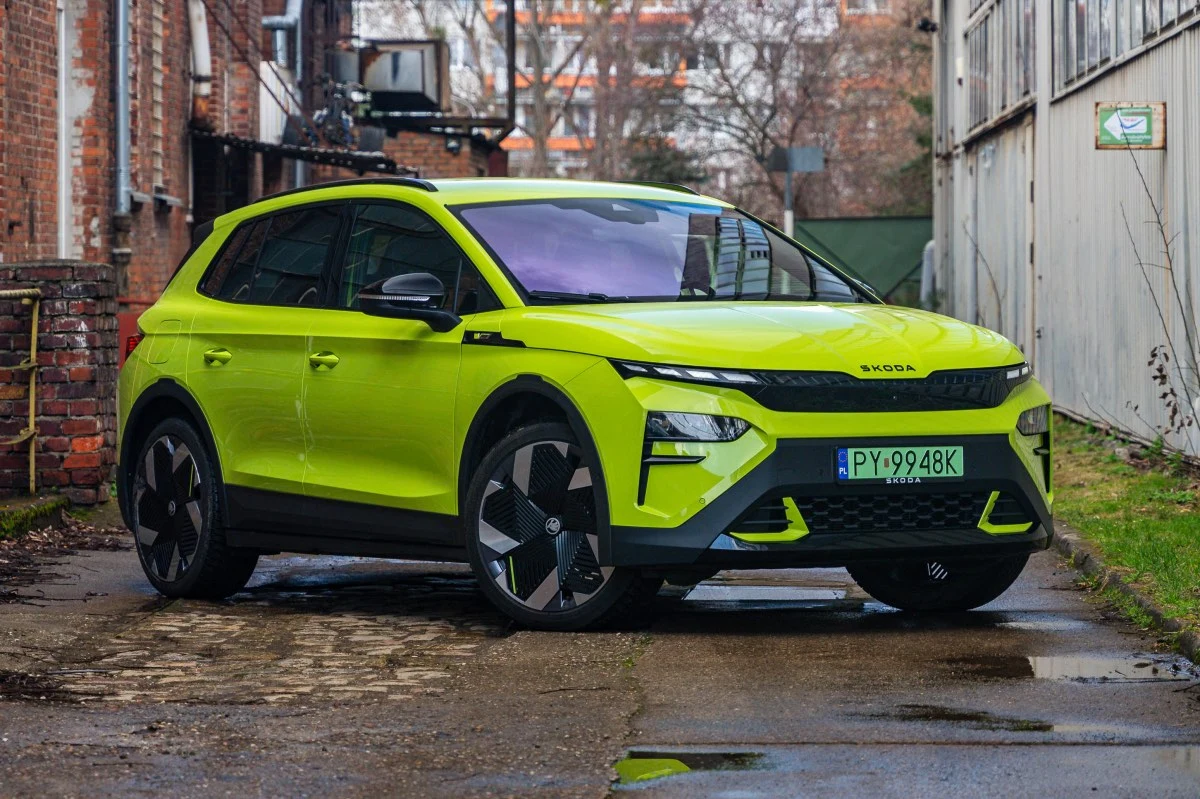 Żółto-zielony kolor Elroqa RS przyciąga spojrzenia gdziekolwiek pojawia się to auto. Limonkowa Škoda w nowoczesnej stylistyce, z czarnymi akcentami na zderzakach i lusterkach, stojąca na dużych felgach o aerodynamicznym wzorze, zaparkowana na brukowanej alejce wśród ceglanej i metalowej zabudowy.