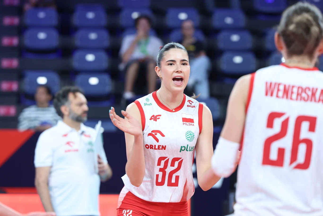 Maja Koput w trakcie mistrzostw Europy Siatkarka w stroju reprezentacji Polski z numerem 32 energicznie gestykuluje, komunikując się z koleżanką z drużyny podczas meczu.