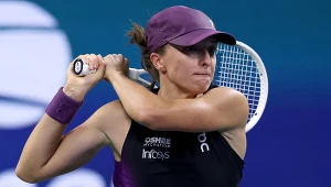Tenisistka w czapce i sportowym stroju podczas dynamicznego zamachu rakietą do tenisa na korcie.