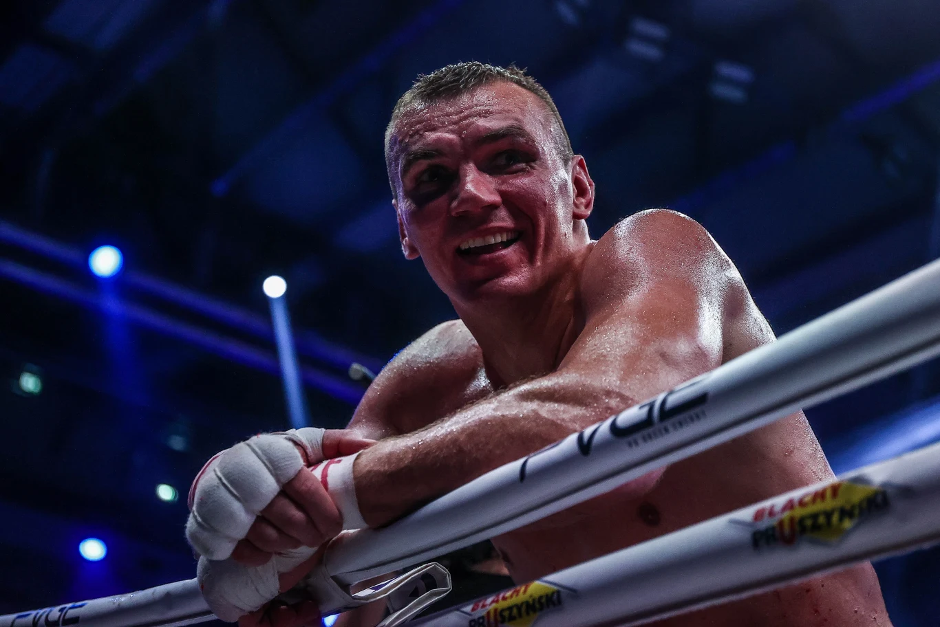 Mateusz Masternak czuje się sportowcem spełnionym. Wywalczył m.in. dwukrotnie tytuł mistrza Europy Zmęczony bokser opierający się o liny ringu z rękami owiniętymi bandażami, oświetlony światłem reflektorów areny.