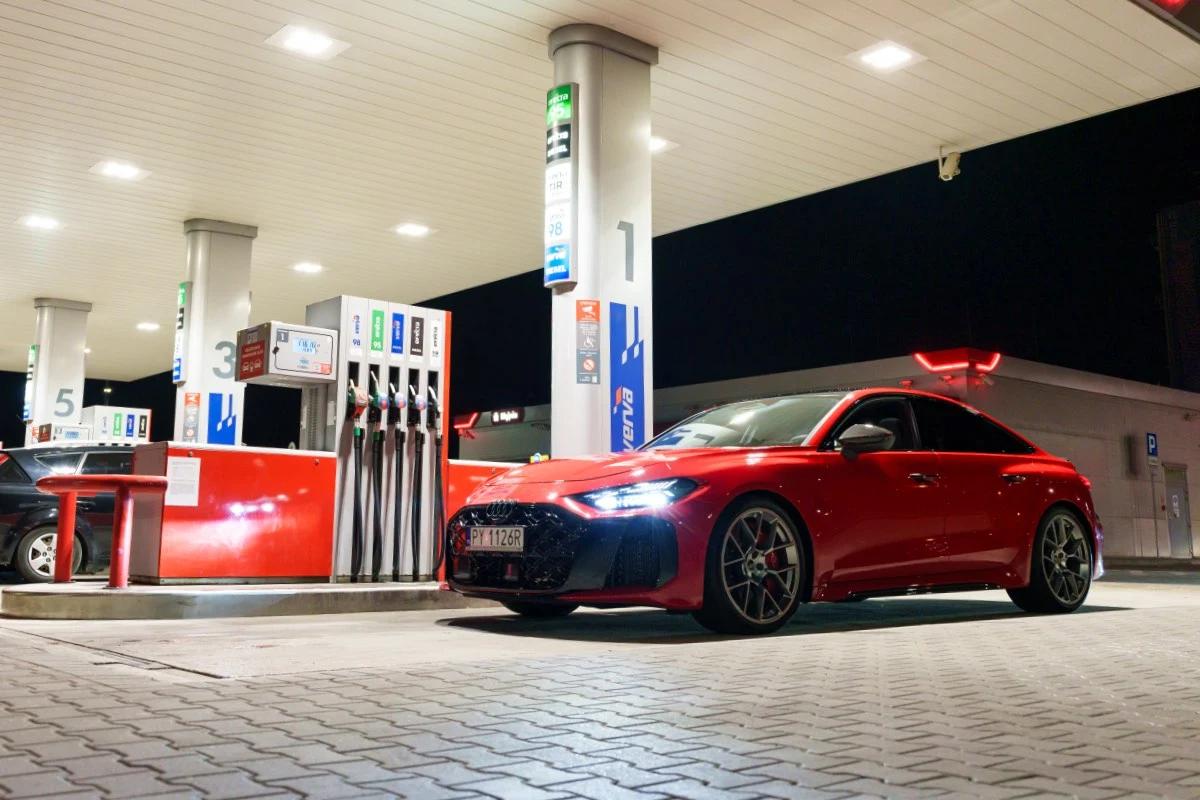 Pojechałem sprawdzić zmianę cen po wygaśnięciu programu CPN. Czerwone sportowe auto przy dystrybutorach paliwa na stacji benzynowej nocą po zakończeniu programu CPN.
