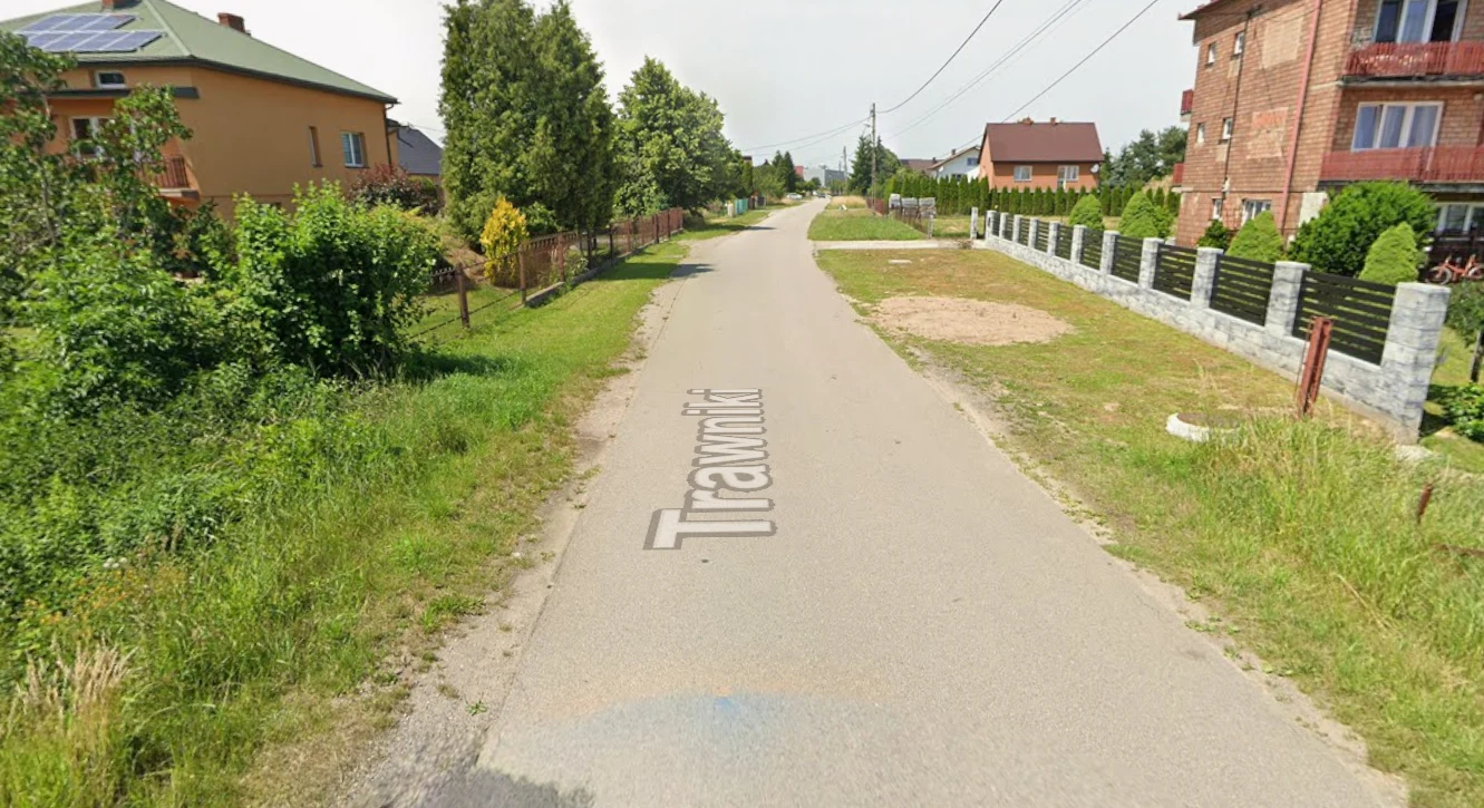 Podłęże, ulica Trawniki Ulica Trawniki w Podłężu – asfaltowa droga otoczona zielenią, domy jednorodzinne, linie energetyczne.