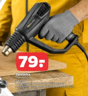 Osoba w żółtym ubraniu roboczym używająca opalarki z wyświetlaczem LCD, trzymająca urządzenie w dłoni w szarej rękawicy nad drewnianą powierzchnią; obok widoczna cena i podstawowe informacje o produkcie.