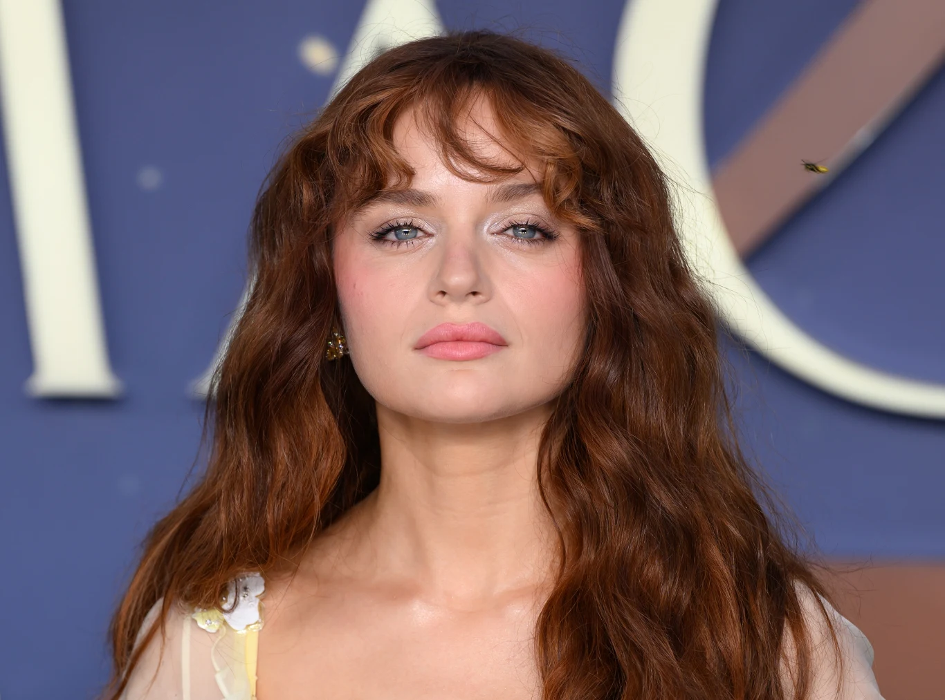 Joey King na pokazie filmu "Totalna magia 2" Joey King na pokazie filmu 'Totalna magia 2', długie rude włosy, jasna cera, rozmyte tło z napisem.
