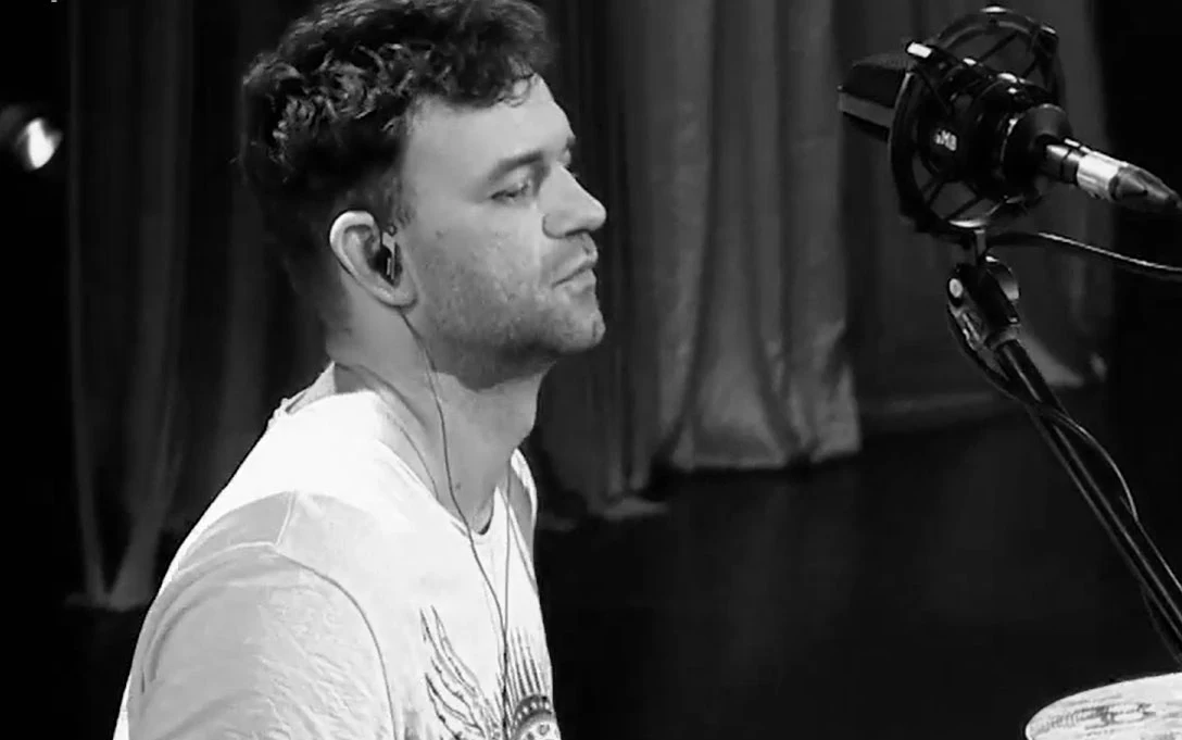 Łukasz Ratuszny (UFly) w programie "Must Be The Music" Łukasz Ratuszny z UFly w białej koszulce przy mikrofonie na scenie programu „Must Be The Music”