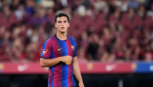 Piłkarz w stroju FC Barcelony z numerem 26 na szortach stoi na boisku podczas meczu.