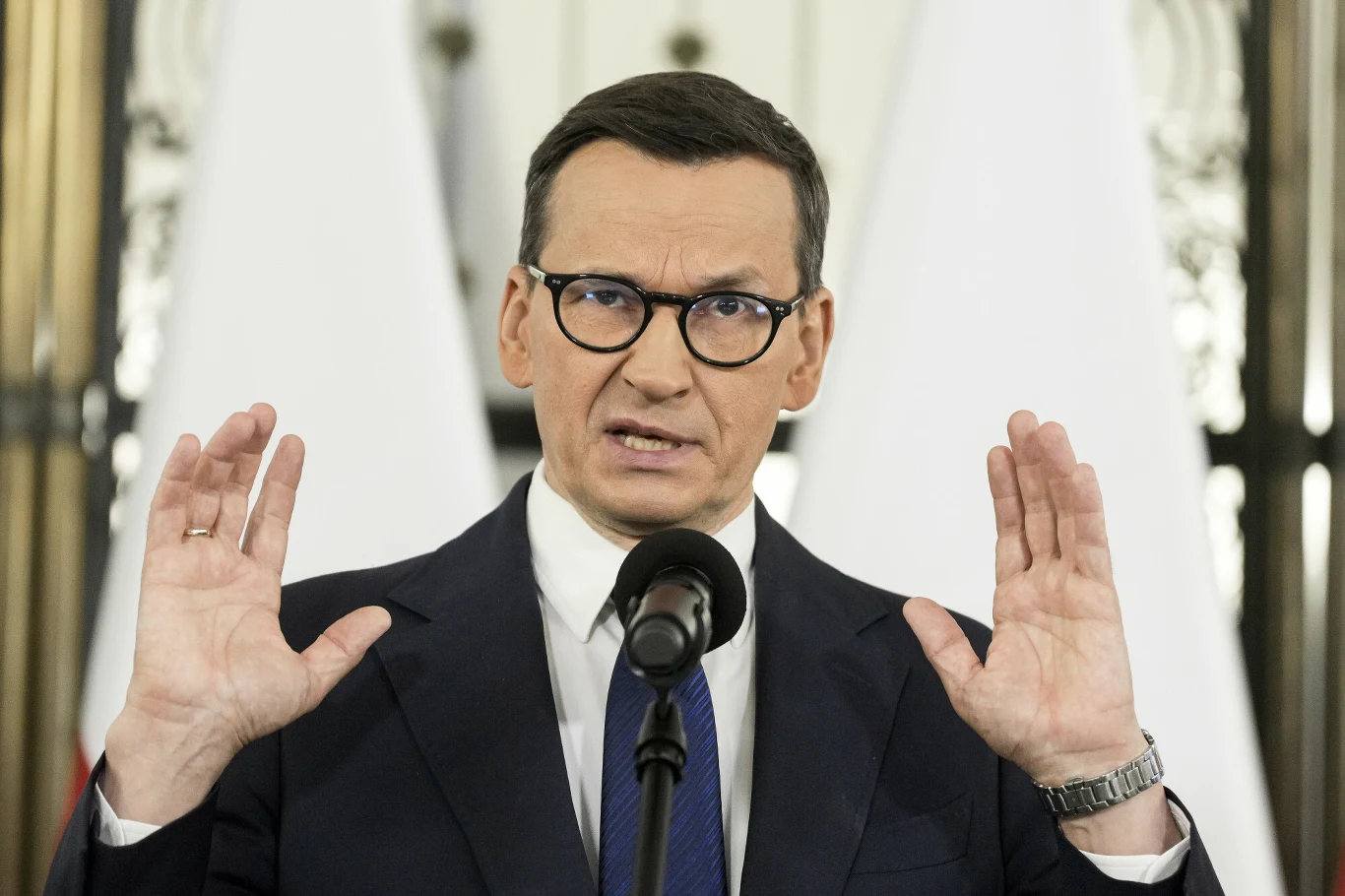 Rozwój Plus chciałby zdobyć fotel wicemarszałka Sejmu. Problem w tym, że PiS także Mężczyzna w garniturze i okularach przemawia do mikrofonu, unosi ręce, w tle dwie biało-czerwone flagi.