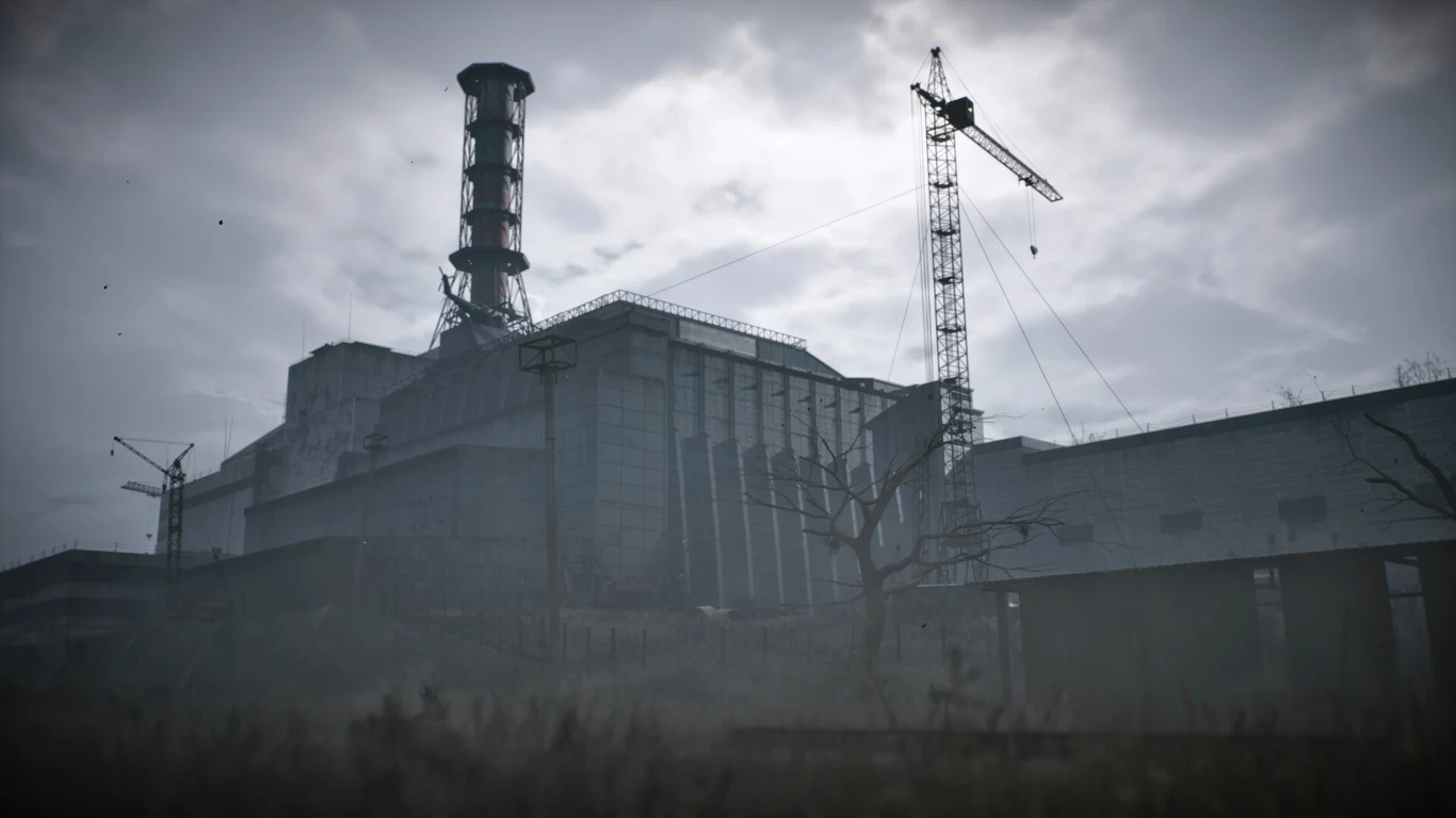 Duży, betonowy budynek elektrowni atomowej z charakterystycznym kominem, dźwigiem budowlanym oraz martwymi drzewami na pierwszym planie, całość spowita szarą, pochmurną atmosferą.