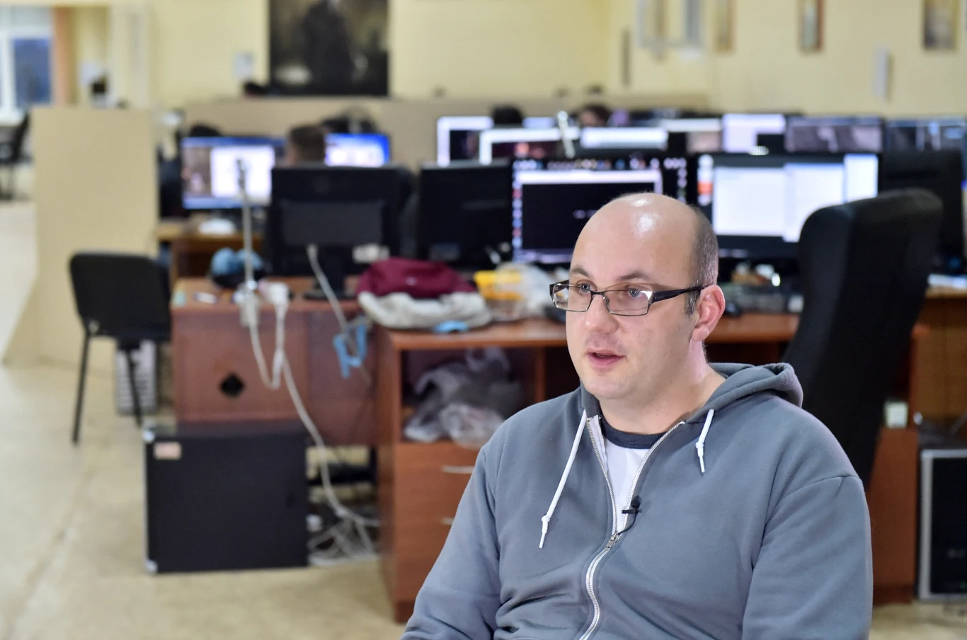 Wael Amr, dyrektor generalny Frogwares podczas wywiadu z 2014 roku w studio w Kijowie Mężczyzna w okularach siedzący przy biurku w przestrzeni biurowej z wieloma stanowiskami komputerowymi w tle.