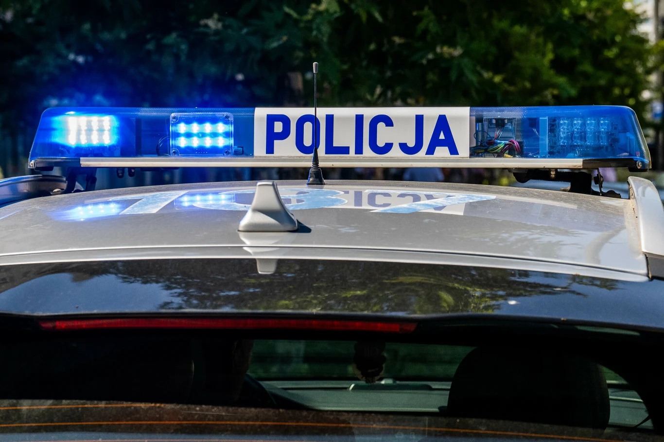 Radiowóz policyjny na sygnale. Zdj. ilustracyjne Radiowóz policyjny z włączonymi niebieskimi światłami sygnalizacyjnymi i napisem 'Policja' na dachu.