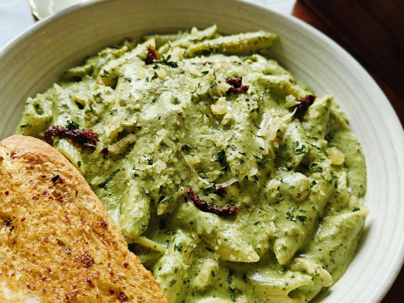 Pesto z natki pietruszki świetnie sprawdza się jako dodatek do makaronów. Makaron penne z zielonym pesto z natki marchewki, kawałkami suszonych pomidorów i startym serem, podany z pieczywem czosnkowym