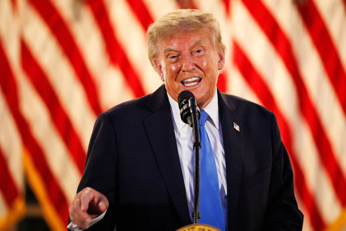 Prezydent Donald Trump krytykuje Hiszpanię Donald Trump w garniturze i niebieskim krawacie przemawia do mikrofonu na tle czerwono-białych flag.