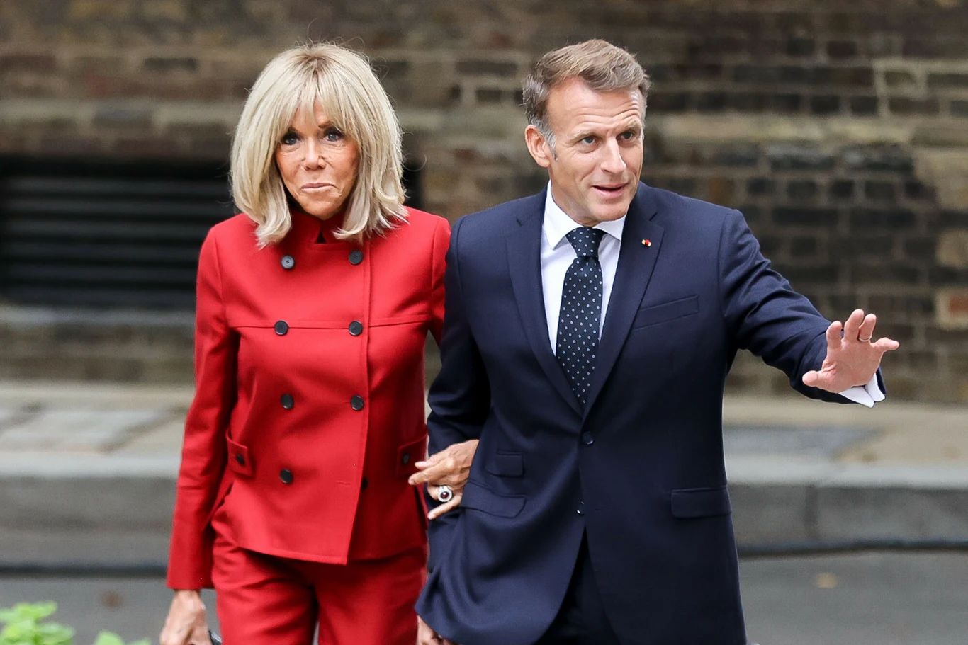 Prezydent Francji z wizytą w Londynie. Brigitte Macron zachwyciła w stylowym, czerwonym garniturze Brigitte Macron w czerwonym garniturze idzie obok prezydenta Francji w granatowym garniturze i krawacie w kropki.