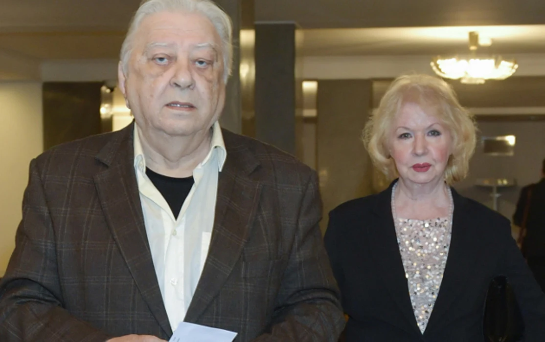 Halina Kowalska, Włodzimierz Nowak Starszy mężczyzna w brązowej marynarce, trzymający kartkę, stoi obok kobiety w eleganckim, czarnym stroju z jasną bluzką ozdobioną cekinami.