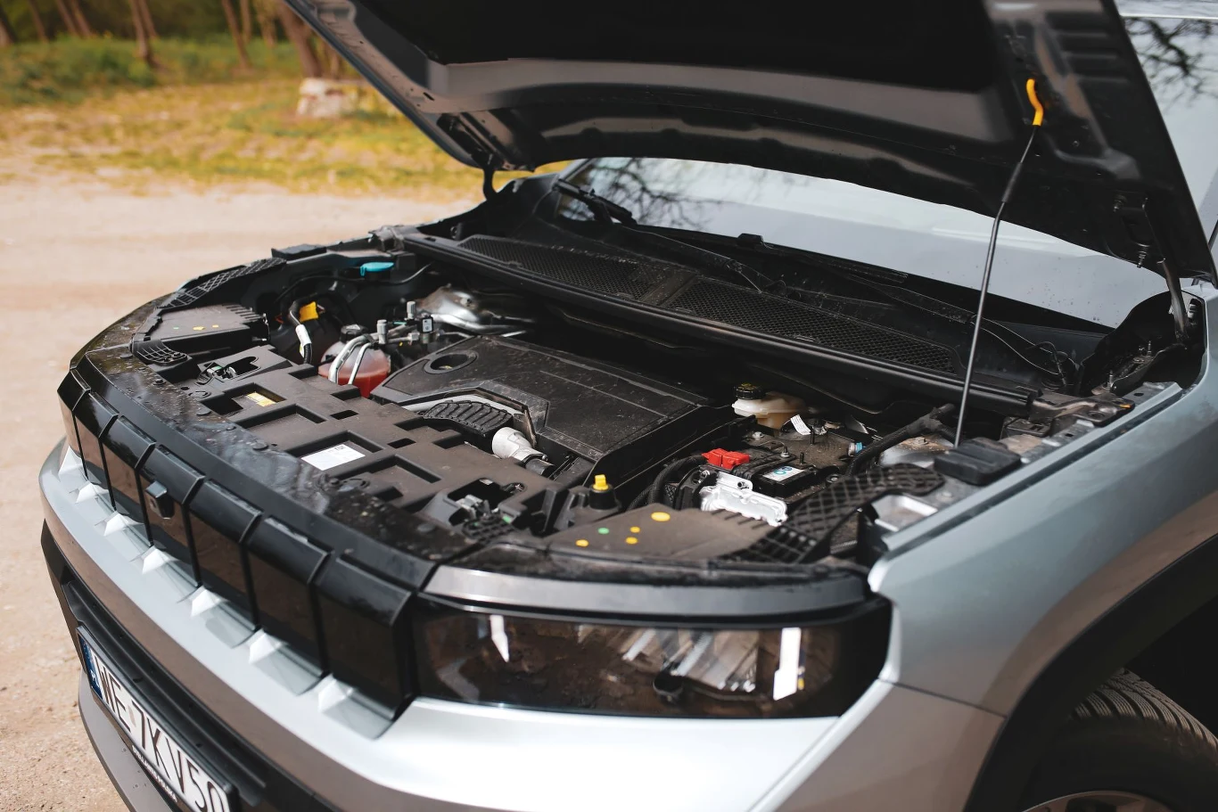 W podstawowej wersji napędowej znajdziemy trzycylindrowy silnik benzynowy o pojemności 1,2 l wspomagany przez jednostkę elektryczną. Moc systemowa wynosi 145 KM. Silnik nowoczesnego samochodu osobowego z otwartą maską, widoczne elementy jednostki napędowej oraz podzespoły techniczne.