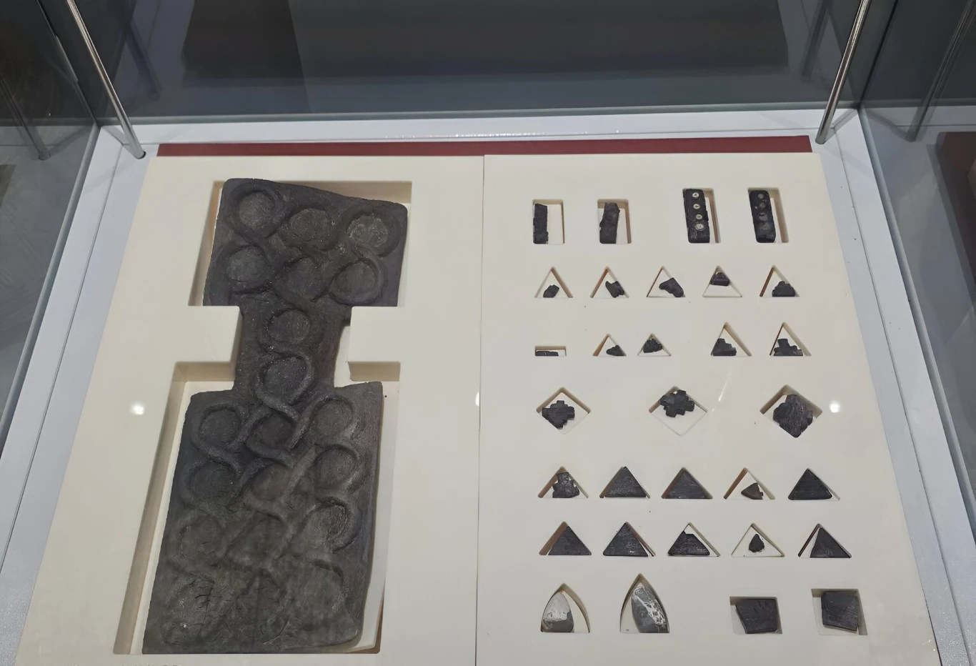 Archeolodzy znaleźli w Iranie nieznaną grę planszową sprzed 4600 lat (zdjęcie ilustracyjne), Fragment starożytnej gry planszowej z Shahr-i Sokhta. Czarne pole z wgłębieniami i pionki w muzealnej gablocie.