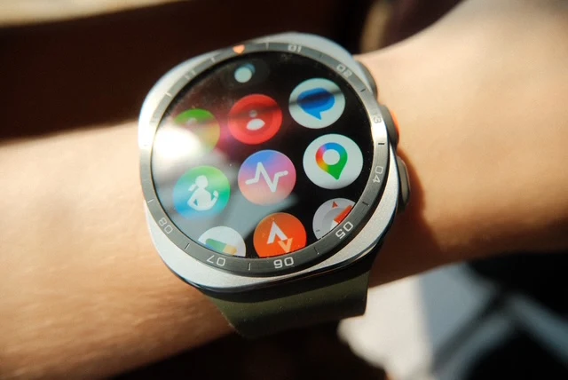 smartwatch z okrągłym ekranem prezentujący kolorowe ikony aplikacji fitness, zdrowia i map na nadgarstku osoby