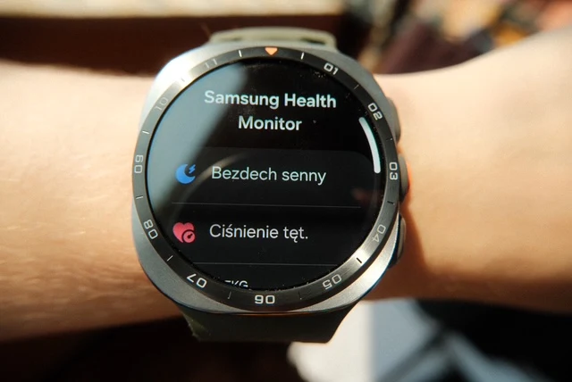 Zegarek smartwatch na nadgarstku z wyświetlonym ekranem aplikacji Samsung Health Monitor pokazującym opcje monitorowania bezdechu sennego i ciśnienia tętniczego.