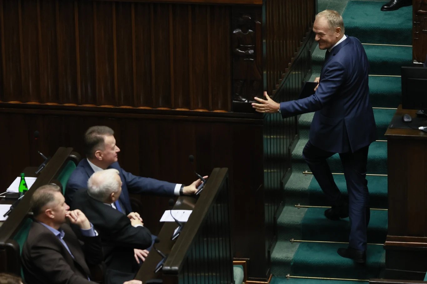 Donald Tusk podczas wystąpienia w Sejmie Donald Tusk w garniturze wchodzi po schodach w Sejmie, trzech parlamentarzystów zwraca na niego uwagę