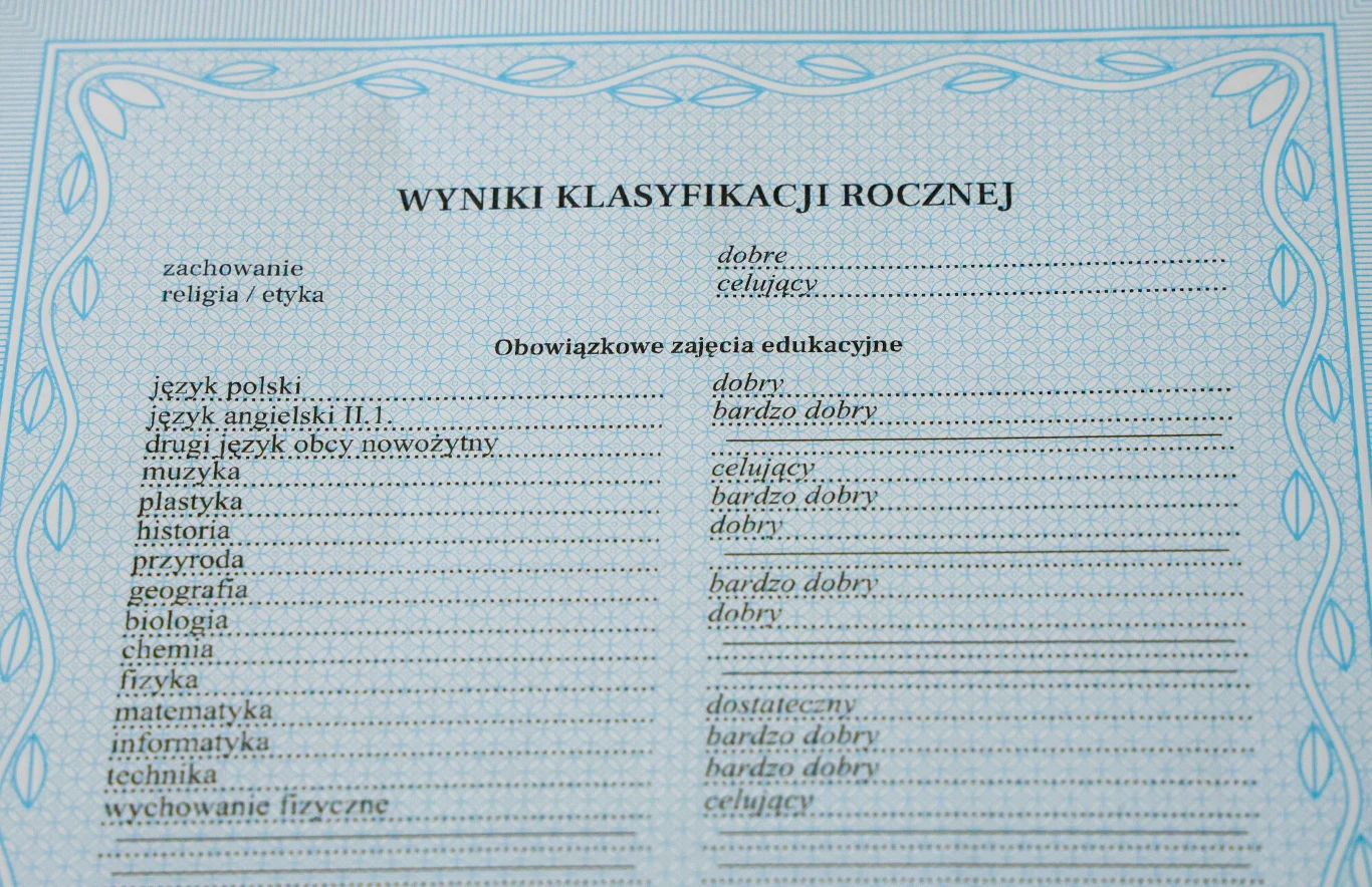 Świadectwo szkolne z wypełnionymi ocenami z przedmiotów obowiązkowych, zdobione niebieską ramką, zawierające kategorie takie jak zachowanie, religia i etyka oraz wyniki z przedmiotów takich jak język polski, matematyka, biologia, informatyka i wychowan...
