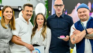 Pięć uśmiechniętych osób w kolorowych ubraniach pozuje razem w pomieszczeniu; jedna trzyma podkładkę z logo '"halo tu polsat", inna kawałek ciasta na talerzyku.