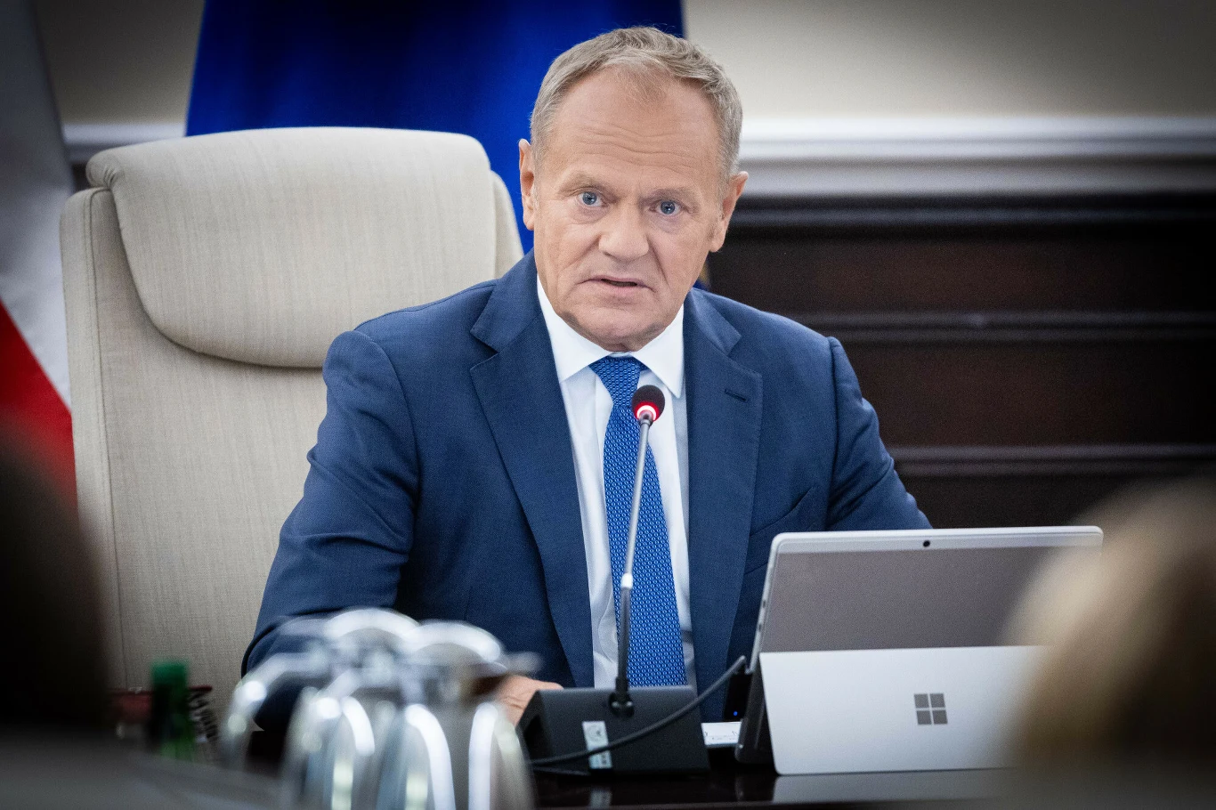 Sondaż CBOS: Polacy ocenili rząd i premiera Donalda Tuska Premier Donald Tusk w garniturze przy stole konferencyjnym z laptopem i mikrofonem podczas posiedzenia rządu.