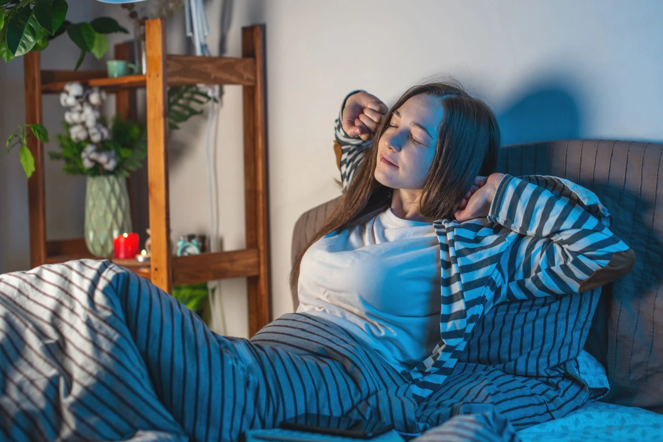 Glicyna kojarzy się głównie z kolagenem, ale coraz częściej mówi się także o jej wpływie na sen. Badania wskazują, że przyjmowana przed snem może wspierać jego jakość Młoda kobieta w piżamie przeciąga się, siedząc na łóżku o poranku w jasnym pokoju.