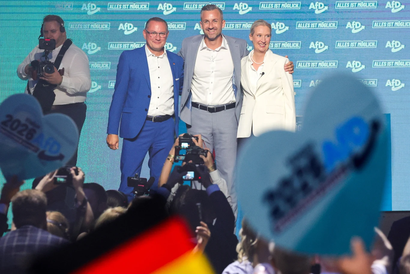Niemcy: W Saksonii-Anhalt odbywają się wybory regionalne, AfD z szansą na zwycięstwo Liderzy AfD na scenie z symbolami partii, w tle tłum, niebieskie balony z logo i niemiecka flaga.