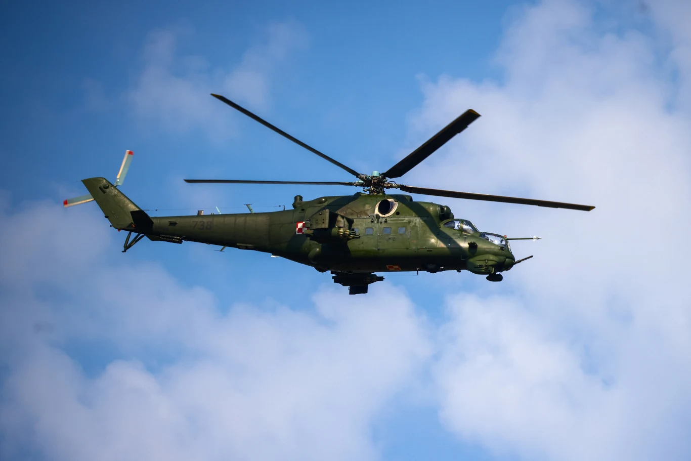 Ppłk Jacek Goryszewski przekazał, że w rejon zdarzenia wysłano śmigłowiec Mi-24, fot. ilustracyjna Wojskowy śmigłowiec Mi-24 w zielonym malowaniu na tle nieba z białymi chmurami, zdjęcie ilustracyjne.