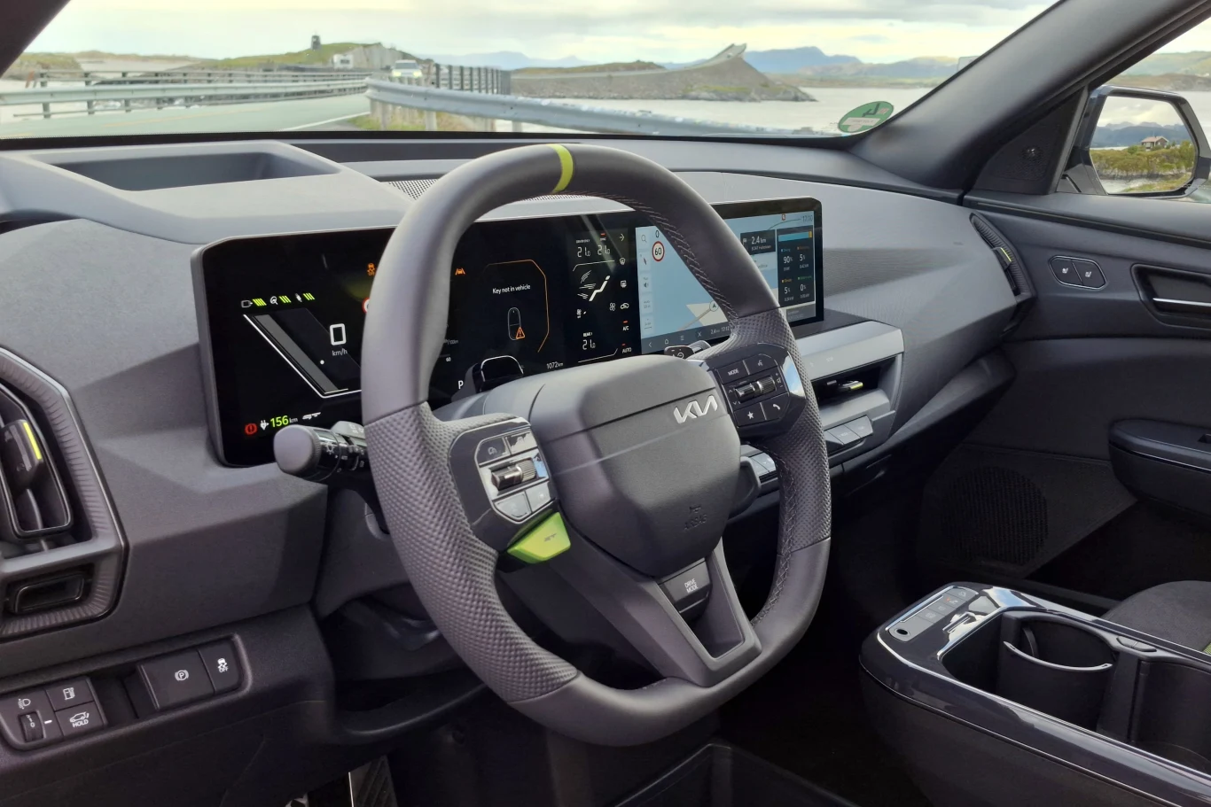 Kia EV5 GT Nowoczesna kierownica z wyraźnym logo Kia, cyfrowy wyświetlacz zegarów oraz ekran multimedialny umieszczone na minimalistycznej desce rozdzielczej elektrycznego samochodu.