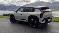 Nowoczesny SUV w jasnej kolorystyce z kontrastującymi, czarnymi akcentami nadwozia zaparkowany na asfaltowej drodze przy malowniczym jeziorze, w otoczeniu górskich krajobrazów.