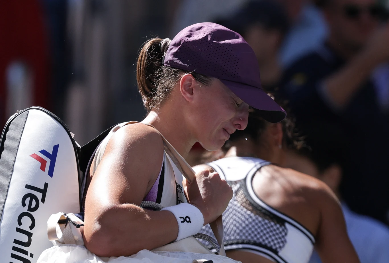 Iga Świątek smutna opuszczała Arthur Ashe Stadium Zawodniczka tenisowa w czapce z daszkiem i sportowym stroju niesie na ramieniu torbę, wyglądając na zamyśloną podczas opuszczania kortu.