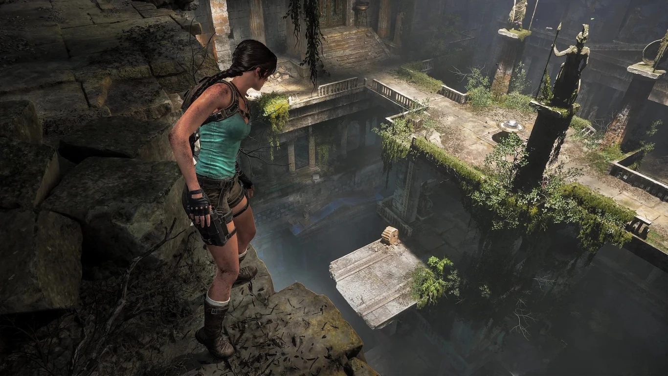 Tomb Raider: Legacy of Atlantis Lara Croft stoi na skalnej półce, obserwując kamienny most i ruiny z posągami oraz kolumnami w tle.